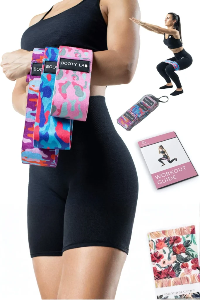 A fitness product collage showcased in "Fabric Resistance Loops & Booty Bands.jpg", featuring an athletic woman from the waist down wearing black gym shorts and holding three colorful, patterned fabric resistance loops with the "BOOTY LAB" logo. The background is plain white, displaying a mesh carrying pouch, a printed workout guide booklet, a floral pattern mat or towel, and a smaller graphic of a woman in a black sports bra and leggings performing a deep squat while wearing one of the thick fabric bands around her thighs.