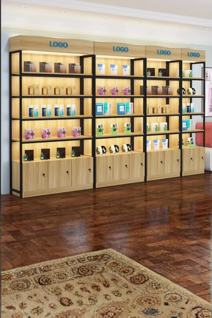 A beautifully curated wall setup showing clever beauty room ideas at home. The image highlights minimalist white floating shelves installed vertically on a light wall next to a mirror. The shelves are neatly styled with luxury perfume bottles arranged by height, high-end makeup palettes, foundations, and elegant decorative accents like a small vase, creating a clean, professional display.