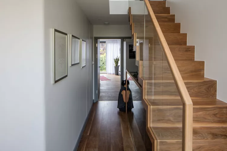 Framed glass stair railing featuring sleek wooden handrails and clear glass panels, highlighting modern indoor stair railing ideas.
