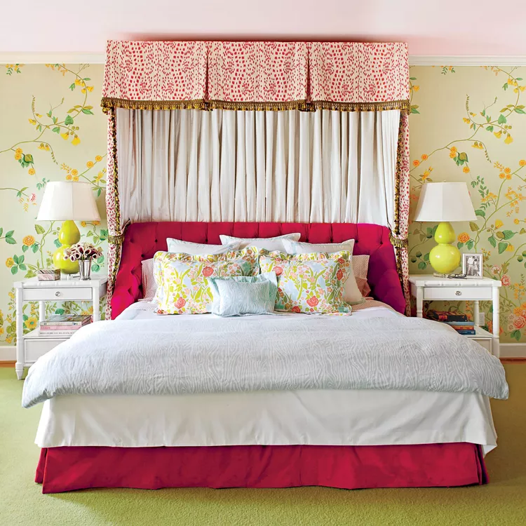 A maximalist master bedroom showcasing unified bedroom flooring ideas carpet choices by running soft flooring from baseboard to baseboard. The room features a seamless, solid olive green wall-to-wall carpet that creates a warm, cohesive foundation under an ornate tufted magenta canopy bed. The bold layout is balanced with soft yellow floral wallpaper, white traditional nightstands, and matching bright green table lamps.