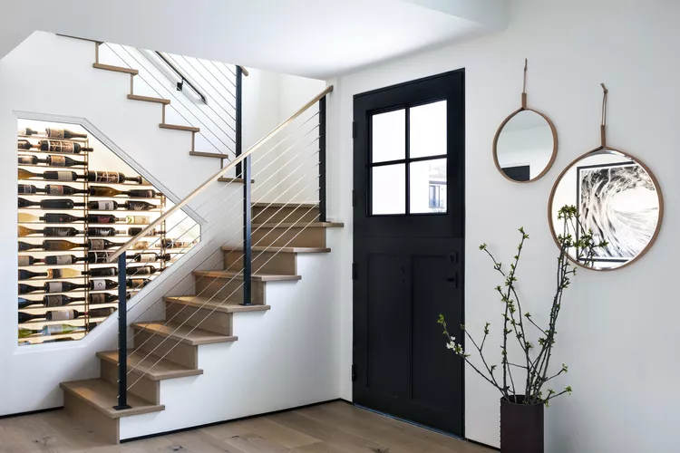 Mixed material stairs featuring wooden handrails, black posts, and horizontal cables, highlighting modern stair railing ideas indoor.