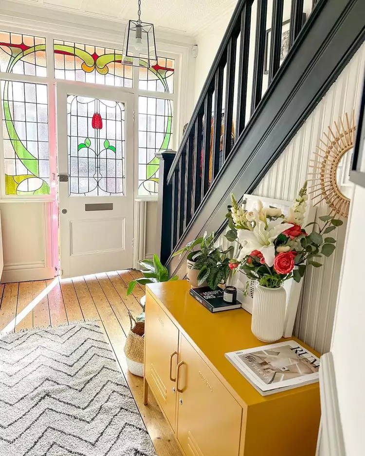 A vibrant stained glass front door panel with matching sidelights and transom window illuminating an elegant entryway, highlighting glass window ideas to set the tone in a luxury foyer.