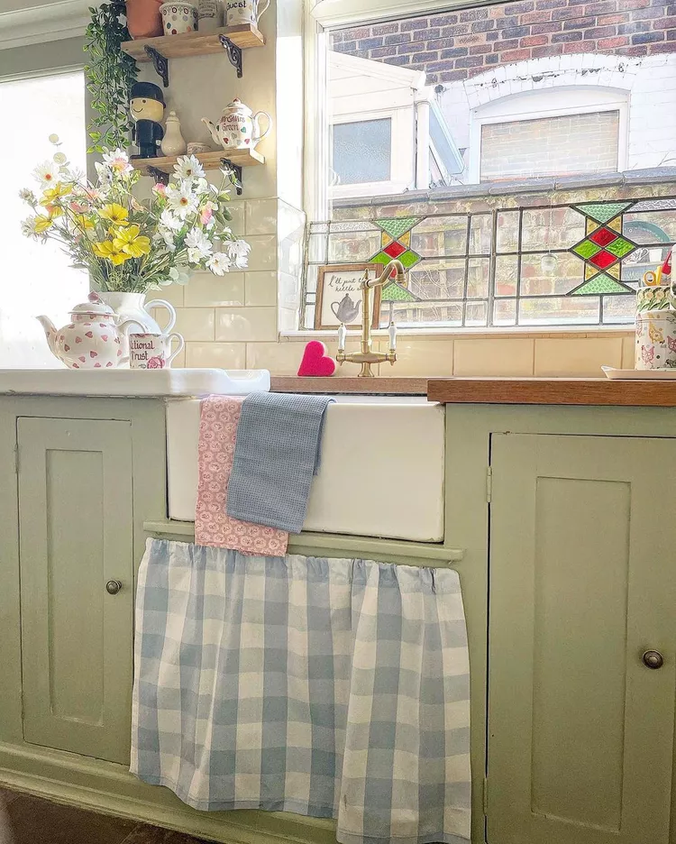 A rustic kitchen sink area featuring a window pane adorned with geometric stained glass details, showcasing creative glass window ideas to transform a farm-style kitchen washing zone.
